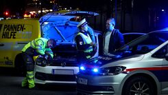 Polizistin klärt Autofahrenden über die Wichtigkeit einer ausreichenden Beleuchtung auf. Im Hintergrund wird von einem ÖAMTC-Techniker die Lampe beim Auto getauscht. Die gemeinsame Aktion nennt sich Licht statt Strafe.