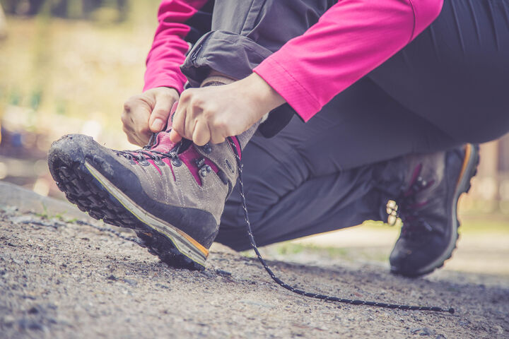 Wanderschuhe, die gerade zu gemacht werden von der Person, die sie trägt.
