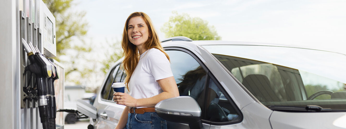 Eine Dame steht vor neben einem Auto vor einer Zapfsäule