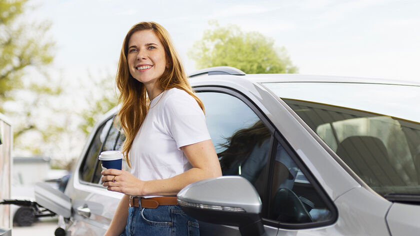 Eine Dame steht vor neben einem Auto vor einer Zapfsäule