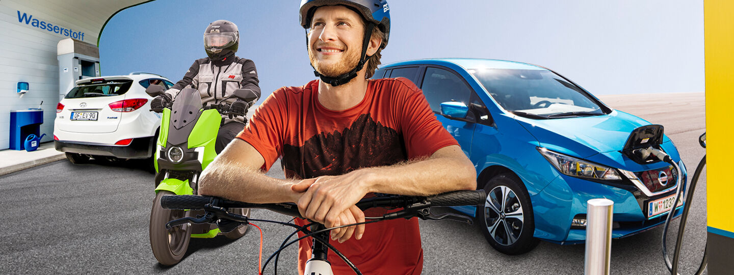 Ein Radfahrer mit Helm, ein E-Mopedfahrer mit Helm und ein blaues E-Auto beim Laden an einer Tankstelle. Im Hintergrund ist eine Wasserstoff Lademöglichkeit.