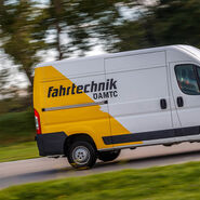 Weiß-Gelber Kastenwagen mit ÖAMTC Fahrtechnik Logo auf einer Straße