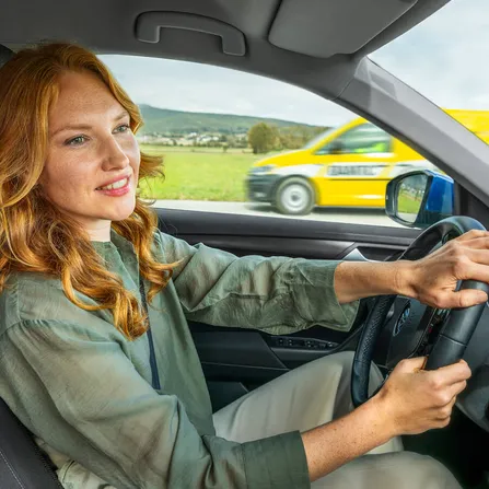 Eine Dame im inneren eines Fahrzeuges hält das Lenkrad.