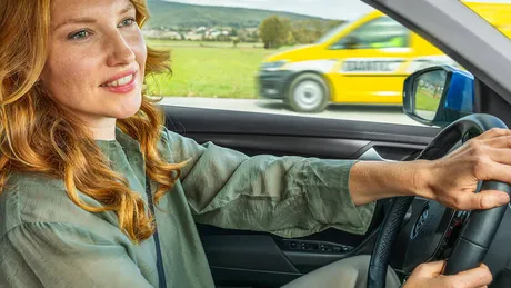 Eine Dame im inneren eines Fahrzeuges hält das Lenkrad.