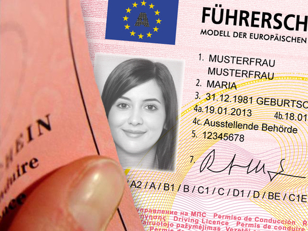 Der Ausschnitt eines rosa Führerscheins im Scheckkartenformat. In der Mitte ist ein Foto einer Frau mit langen Haaren in schwarz-weiß. Rechts neben dem Foto der Frau stehen ihre persönlichen Informationen am Führerschein.