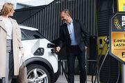 Eine Frau und ein Mann stehen vor einem E-Auto und der Mann hält das Ladekabel in der Hand. Abzeichen Best4Fleet Award.