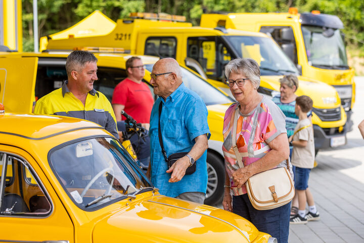 Gespräch zwischen einem ÖAMTC Pannenfahrer und Besuchern beim Publikumstag am Stützpunkt Melk zwischen der Pannenflotte