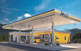 Eni Tankstelle mit Zapfsäulen, Waschanlage und Shop. Im Hintergrund blauer Himmel und Berge.