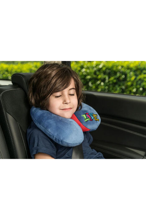 Ein Junge sitzt mit geschlossenen Augen und einem Lächeln in einem Auto mit der Nackenrolle um den Hals.