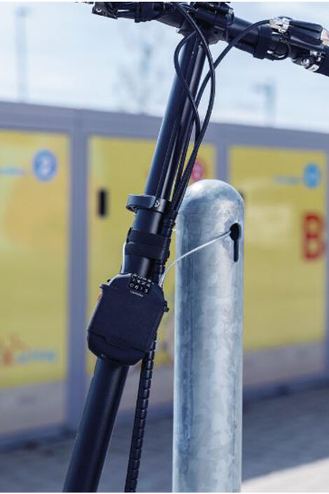 Combiflex Kabelschloss sichert elektrischen Roller an einer Metallstange durch ausziehbares Kabel, dass durch ein Loch in der Metallstange gegeben wurde.