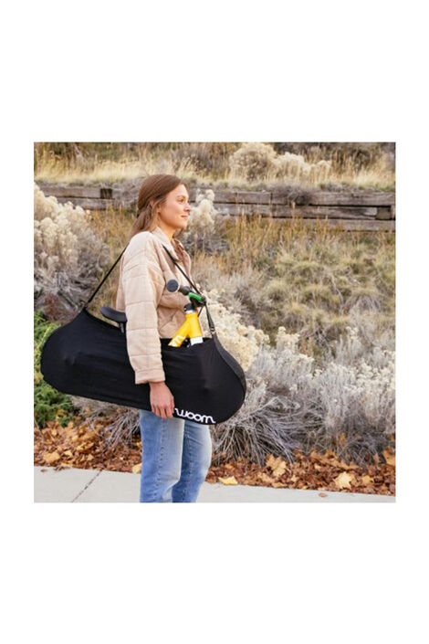 Frau trägt ein Fahrrad von Woom in einer Tragetasche über ihrer Schulter 