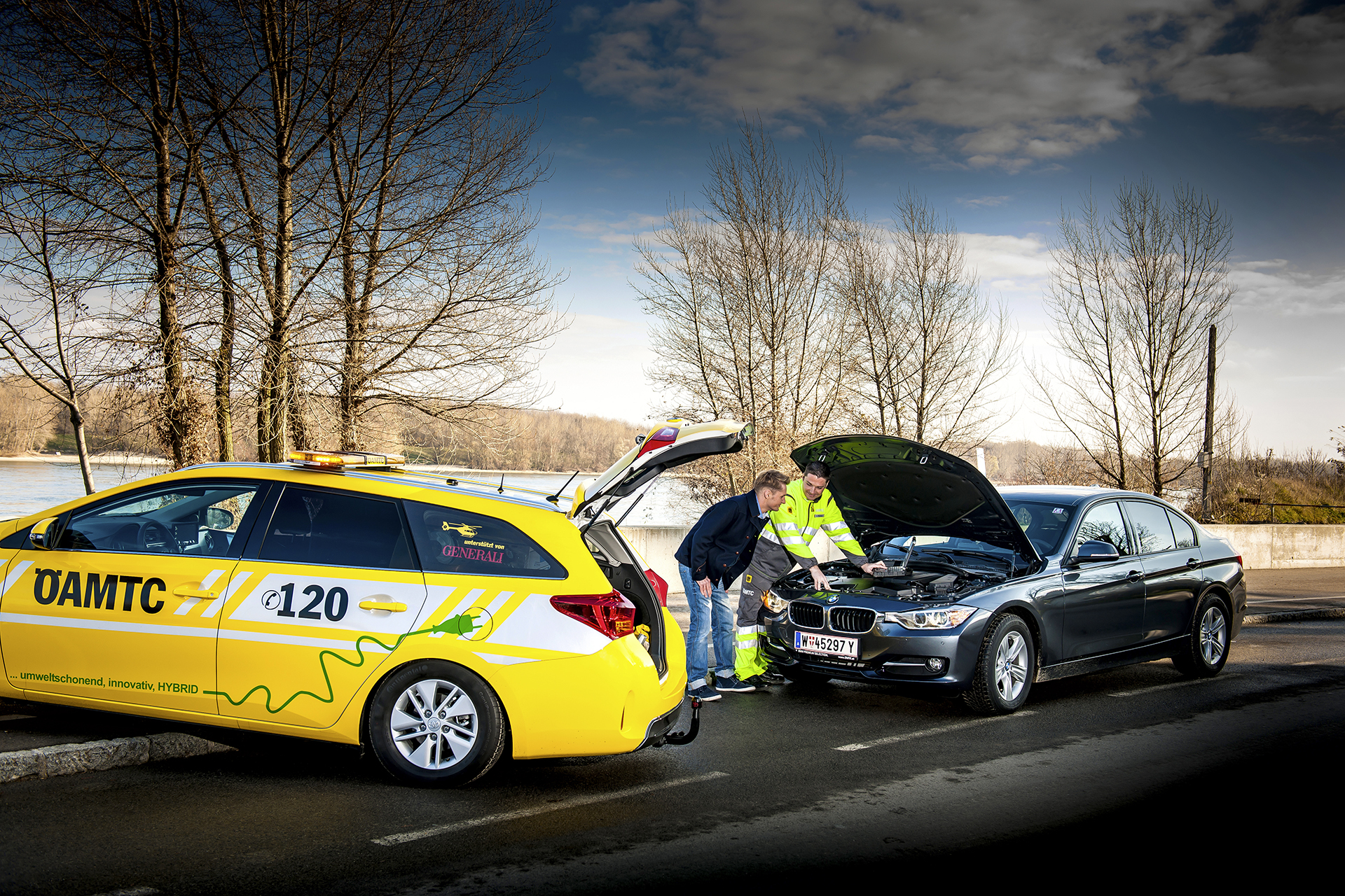 ÖAMTC Techniker mit Mitglied vor geöffneter Motorhaube auf winterlicher Straße