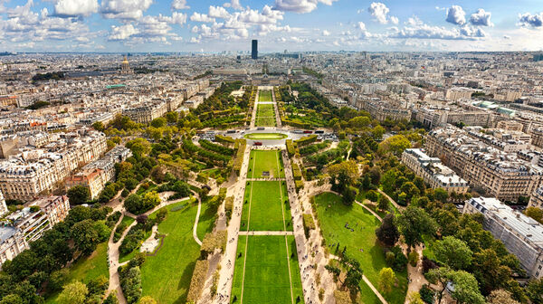 Luftaufnahme des Champ de Mars in Paris mit gepflegten Grünflächen und Wegen, umgeben von der Stadtlandschaft