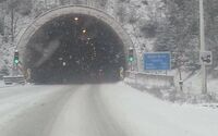 Schneefall vor einem Tunnel auf einer Schnellstraße