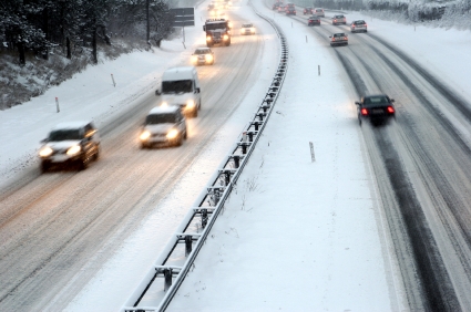 Autos fahren auf einer verschneiten Autobahn, die von Schnee bedeckt ist, bei winterlichen Bedingungen.
