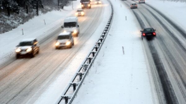 Autos fahren auf einer verschneiten Autobahn, die von Schnee bedeckt ist, bei winterlichen Bedingungen.