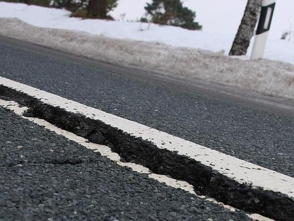 Aufgerissener teil einer Straße im Winter bei Schnee