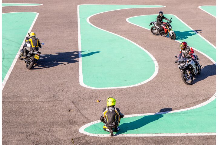 Mehrere Motorradfahrer absolvieren einen Motorrad-Parcours mit engen Kurven auf einem Trainingsplatz