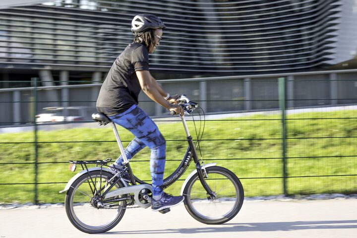 Eine junge Frau übt auf einem Mini-Fahrrad das Radfahren.