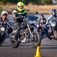 Eine Gruppe von Motorradfahrern fährt hintereinander um Pylonen, an der Spitze ein Fahrtechnik-Instruktor der ÖAMTC Fahrtechnik