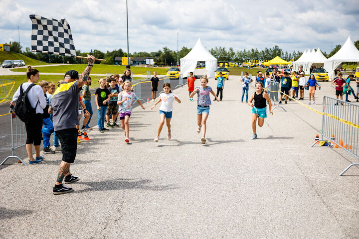 4 Kinder laufen auf eine Zielflagge zu, die gerade geschwungen wird 