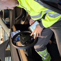 Fahrzeugdiagnose Ein Pannenfahrer sitzt in einem Elektroauto und führt mittels Tablet eine Fahrzeugdiagnose bzw. Pannendiagnose durch.