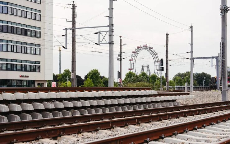 Zugschienen und Strecke, im Hintergrund ein Hochhaus und Stromleitungen.
