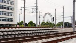 Zugschienen und Strecke, im Hintergrund ein Hochhaus und Stromleitungen.