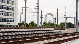 Zugschienen und Strecke, im Hintergrund ein Hochhaus und Stromleitungen.