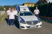 ÖAMTC-Clubmitglieder stehen gemeinsam mit Sanitätern vor einem Krankenfahrzeug.