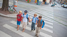 Eine Gruppe von Schulkindern geht über einen Zebrastreifen.