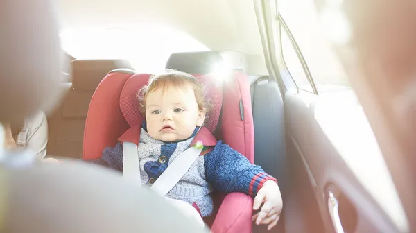 Baby mit Weste, scheint etwas energielos, im Autositz, die Sonne scheint ins Auto.