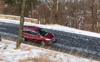 Rotes Auto auf eis- und leicht schneebedeckter Straße.