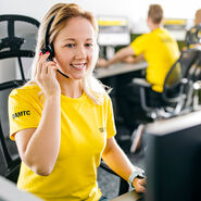 Auf dem Bild sieht man eine Frau in einem kurzärmeligen gelben T-Shirt. Am Ärmels steht ÖAMTC. Sie sitzt vor einem Bildschirm und hat ein Headset auf.