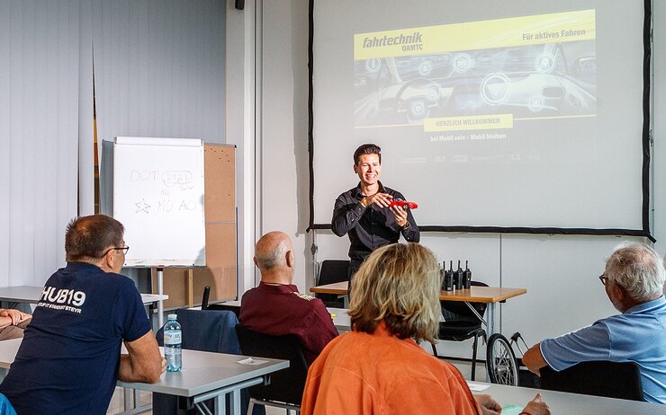 Mobilitätstage für 60+ Schulungsraum im Fahrtechnik Zentrum. Trainer:in erklärt den Teilnehmer:innen Verkehrssituation im Rahmen der Mobilitätstage 60+.