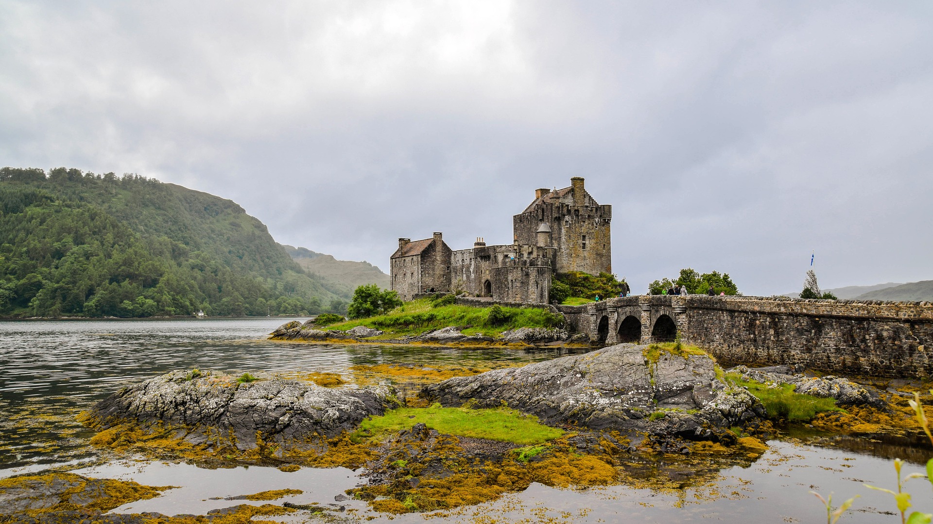 Malerischer Blick auf das Eilean Donan Castle in den schottischen Highlands bei Nebel, umgeben von Wasser und sanften Hügeln