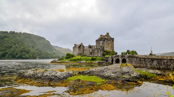 Malerischer Blick auf das Eilean Donan Castle in den schottischen Highlands bei Nebel, umgeben von Wasser und sanften Hügeln