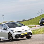 Auf dem Bild sieht man ein weißes und ein schwarzes Auto bei einem Fahrtechnik Training auf der Strecke fahren.