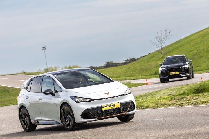 Auf dem Bild sieht man ein weißes und ein schwarzes Auto bei einem Fahrtechnik Training auf der Strecke fahren.