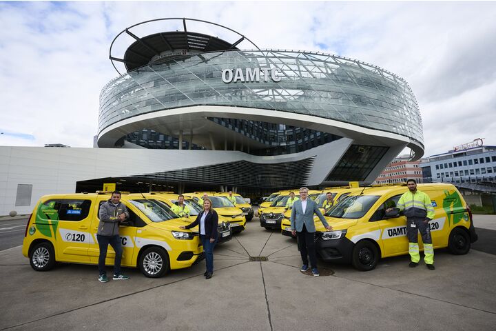 ÖAMTC Pannenfahrzeuge stehen aufgefächert vor dem ÖAMTC Gebäude in Wien Erdberg. Personen stehen bei den Fahrzeugen.