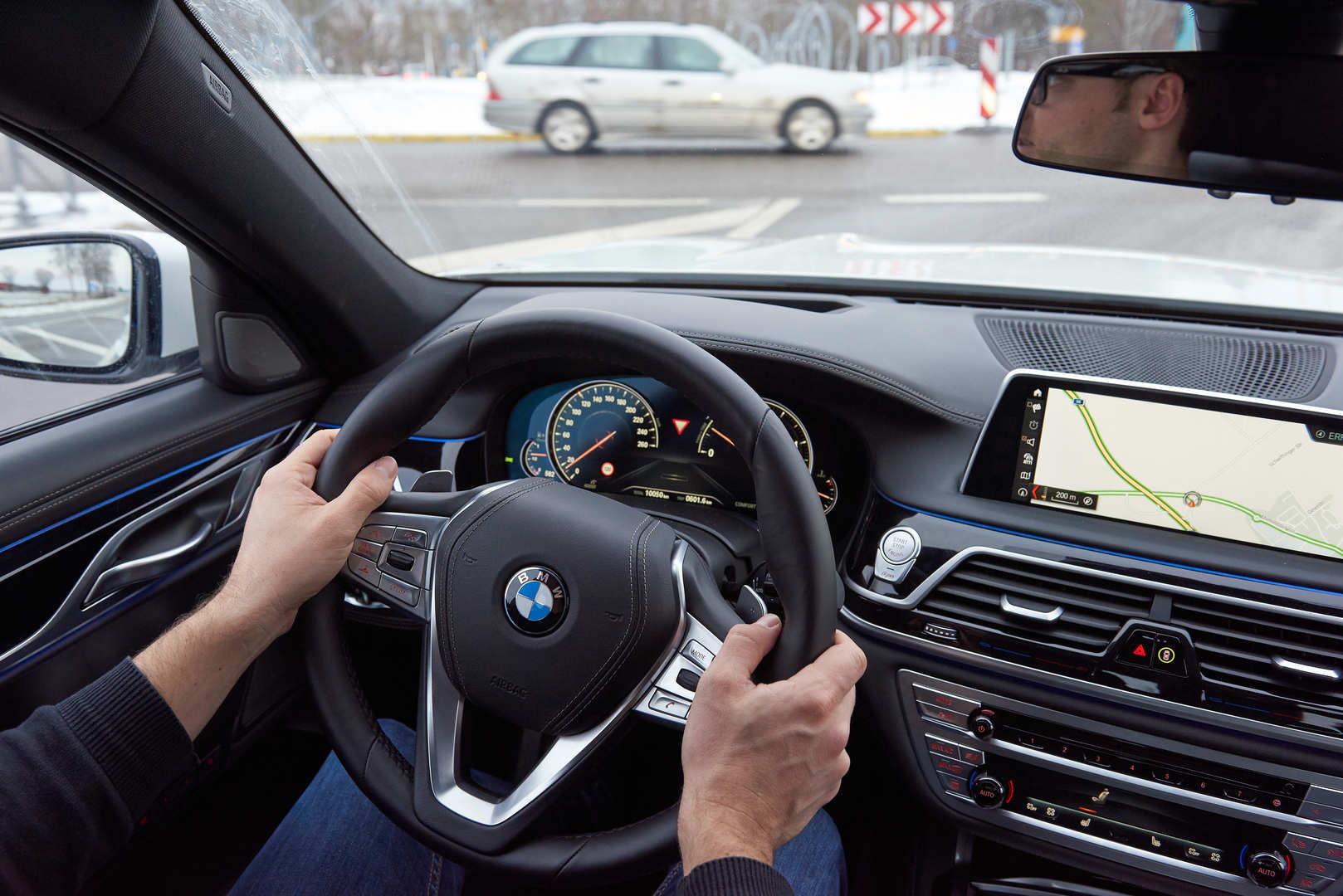 Aus dem Cockpit eines Autos sieht man an einer Kreuzung ein Auto links aus der Querstraße kommend.