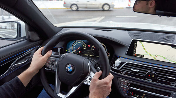 Aus dem Cockpit eines Autos sieht man an einer Kreuzung ein Auto links aus der Querstraße kommend.
