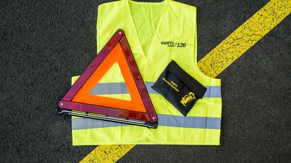 Auf einer Straße liegt eine Warnweste, ein Pannendreieck, eine Motorradapotheke.