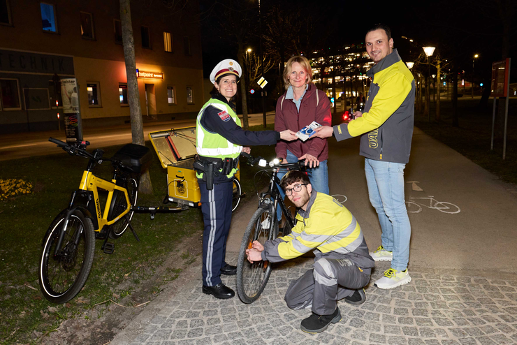 Übergabe von Speichenreflektoren von Polizei und ÖAMTC-Mitarbeiter an Radfahrerin bei der Radlichtaktion in St. Pölten