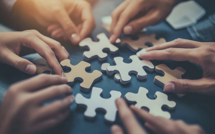 Mehrere Hände die Puzzle Teile verschieben.