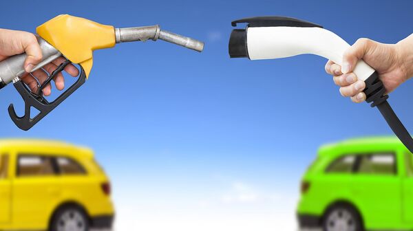 Ein gelber Treibstoff-Zapfhahn und ein weißes Ladekabel für ein Elektroauto zeigen zueinander, im Hintergrund sind ein gelbes und ein grünes Auto.
