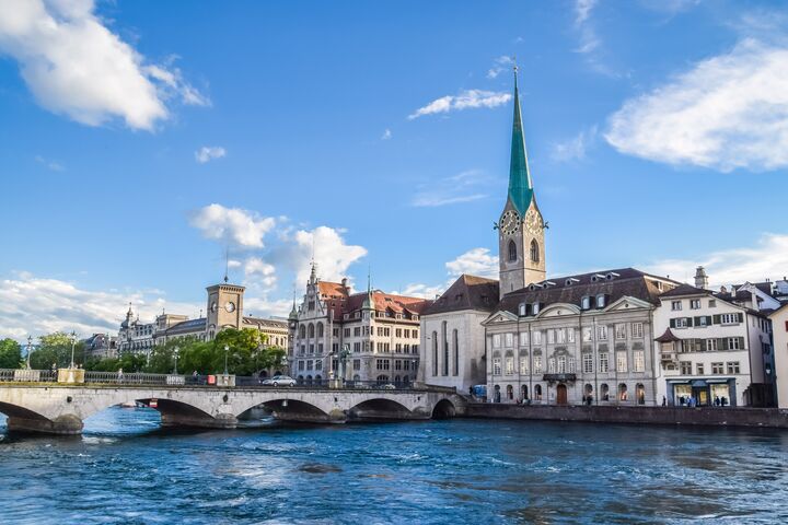 Blick vom Wasser auf mehrere Gebäude am Ufer und die Fraumünsterkirche