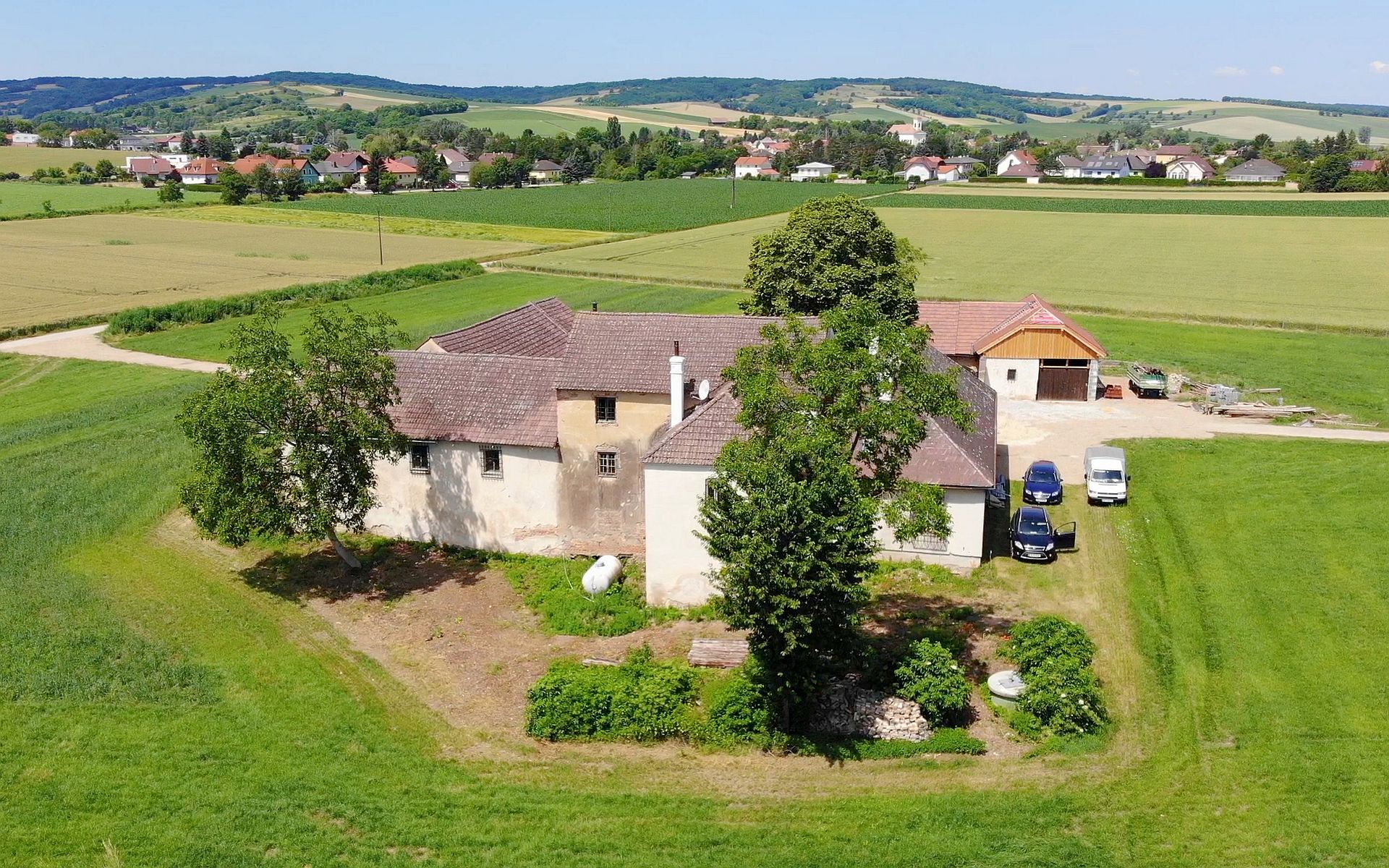 Gebäude der Mühle in Breitenwaida bei Hollabrunn, die Urlaubs-, Therapie- und Beratungszentrum sind, eingebettet in grüner, hügeliger Landschaft.