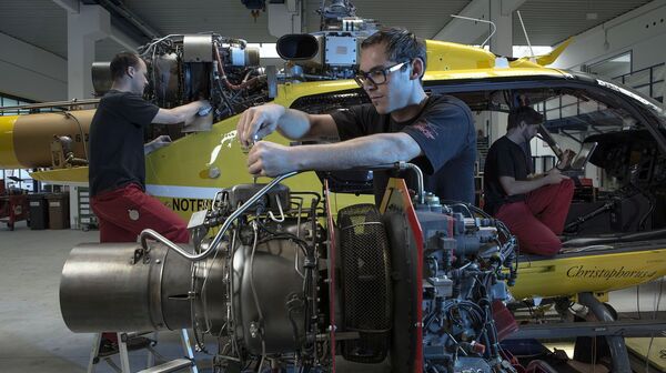 2 Techniker servicieren in einer Wartungs-Halle der HeliAir Triebwerk und Hauptrotor eines Christophorus-Hubschraubers.