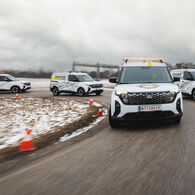 Auf einer Handlingstrecke ist ein Fahrzeugkonvoi von vier Ford E-Transits zu sehen, die für die Geländetechniker der ÖAMTC Fahrtechnik angeschafft worden sind